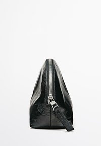 Pochette en cuir noir de forme triangulaire, avec une fermeture éclair argentée et une finition texturée. Dispose d'une petite bride sur le côté.