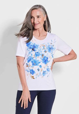 Weißes T-Shirt mit kurzen Ärmeln, das ein blauer Blumenmuster mit hellbraunen Akzenten auf der Vorderseite aufweist. Weicher Stoff mit Rundhalsausschnitt.