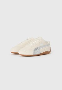 Sneakers Puma in suede crema con dettagli in argento, dotati di una suola in gomma e lacci bianchi. Design slanciato con dettagli del logo stampati in rilievo.