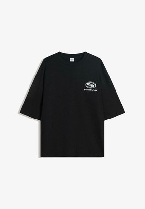 Schwarzes oversized Baumwoll-T-Shirt mit Rundhalsausschnitt und kurzen Ärmeln, auf der Vorderseite mit einem weißen "Shibuya"-Logo bedruckt.