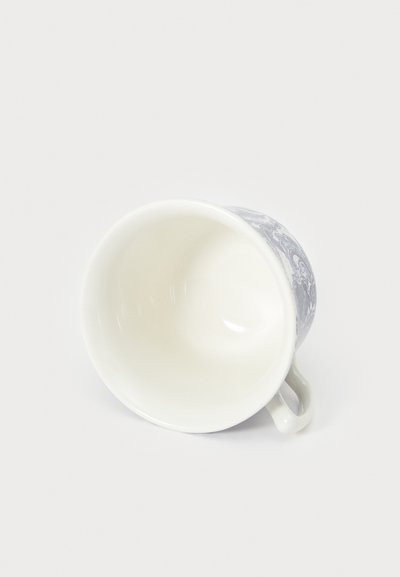 Porseleinen kopje met een gebogen vorm, voorzien van een blauw bloemenpatroon aan de buitenkant. De binnenkant is glad en wit, met een klein handvat.