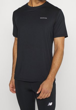 Mann trägt schlichtes schwarzes Kurzarmshirt mit dem Text "ENDURANCE" und schwarze Hose mit weißem New Balance-Logo am Oberschenkel.
