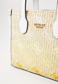 Sac à main en paille tissée crème avec accents jaunes, doté de poignées en cuir blanc et d'un logo brodé. Surface texturée avec un motif décoratif.
