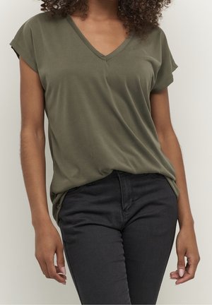 Olivgrünes V-Ausschnitt-T-Shirt aus weichem Stoff mit kurzen Ärmeln, locker geschnitten, kombiniert mit schwarzen Slim-Fit-Jeans.