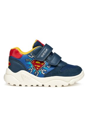 Scarpa da ginnastica per bambini blu navy con interno giallo, tallone rosso, suola bianca, due cinturini in Velcro e logo di Superman con catene sul lato.