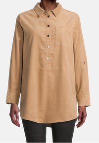 Långärmad, lätt skjorta i tan-färgad tyg, med knappslå framtill, krage, bröstficka och knappar på ärmsluten. Slät textur.