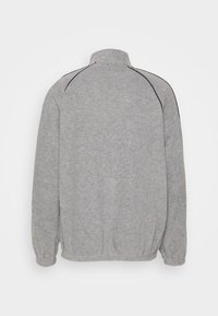 Grå sweatshirt med hög krage, långa ärmar, elastiska muddar och nederkant, med svart accentstygn längs axlarna.