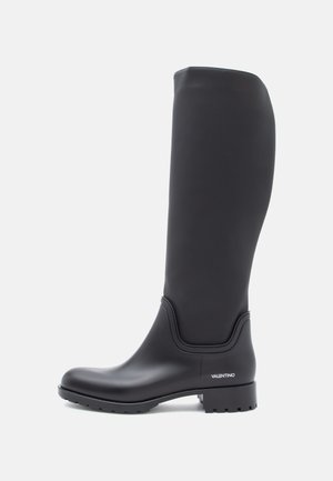 Botas de borracha pretas até ao joelho com uma textura lisa, bico arredondado e salto baixo em bloco. Apresentam uma marcação em branco de um lado.