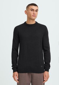 Black, long-sleeve sweater with a crew neckline, made from a soft knitted fabric. Features ribbed cuffs and hem with a small brand label at the waist.