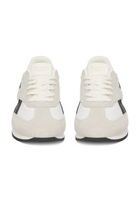 Biele a čierne tenisky vyrobené z semišu a kože, s textúrovaným povrchom, plochými šnúrkami a čiernymi gumovými podrážkami.