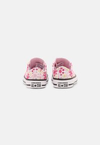 Růžové plátěné tenisky s nízkým designem a černou gumovou podrážkou. Obsahují multicolor květiny a branding "Converse All Star".