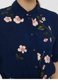 Camicia blu navy con stampa floreale in rosa e verde, caratterizzata da un colletto e chiusura con bottoni frontale. Tessuto morbido con una superficie liscia.