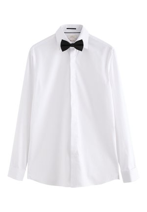 Camicia bianca a maniche lunghe con bottoni nascosti e papillon nero preannodato su sfondo bianco.