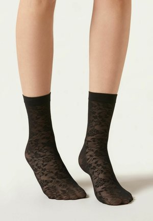 Schwarze Spitzen-Knöchelsocken mit floralen Mustern und einem einfarbigen schwarzen Bündchen, gefertigt aus einem transparenten, dehnbaren Material.