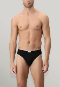 Slip bikini neri realizzati in tessuto morbido, con una vita marchiata e un design minimalista. La vestibilità è aderente e slanciata.