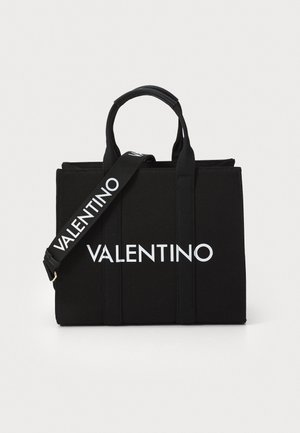 Sort Valentino tote taske med dobbelte håndtag og aftagelig skulderrem, med fedt hvidt Valentino-logo på fronten og remmen.