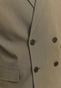 Blazer doppiopetto in un motivo a quadri marroni, caratterizzato da due bottoni neri, revers a punta e tasche laterali. Tessuto testurizzato.