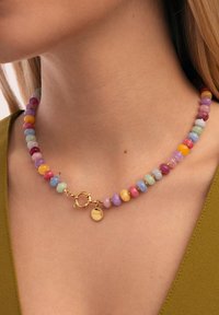 Kleurrijke kralenketting met ronde, gepolijste stenen in pasteltonen, voorzien van een goudkleurige metalen sluiting en een logo-accent.
