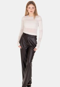 Top crema a manica lunga con dettaglio a righe trasparente abbinato a pantaloni neri in ecopelle a vita alta. Tessuto liscio con design aderente.