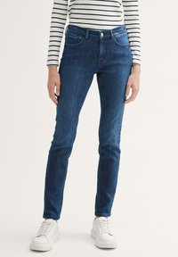 Jeans ajustados en denim azul oscuro con una textura suave, que presentan un diseño clásico de cinco bolsillos y un cierre frontal de botón.