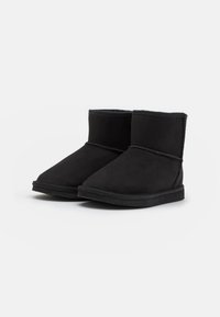 Schwarze Wildleder-Ankle Boots mit runder Zehenpartie, gesteppten Details und einem weichen Innenfutter. Flache Gummisohle, einfaches Design.