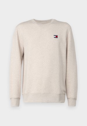 Light beige sweatshirt made from cotton, featuring a crew neck, ribbed cuffs, and a small logo patch on the chest with red and blue elements.