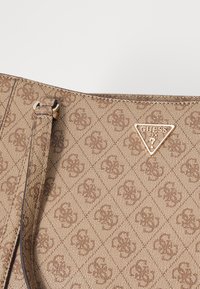 Gouden Guess handtas met een gestructureerde, patronenexterieur met logo-accenten en een afneembare schouderband.
