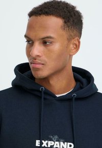 Navy blue hoodie with a drawstring and a front graphic design featuring flowers. Soft fabric texture and relaxed fit.