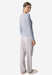 Lyseblå langærmet top med ribbet tekstur, parret med grå rutede vide bukser. Modellen vist fra ryggen, iført bløde slippers.