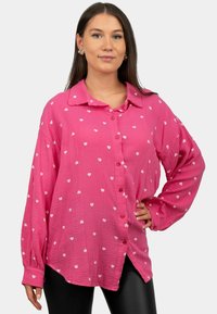 Camicia rosa a maniche lunghe con bottoni, in tessuto testurizzato e motivi a cuori bianchi, con colletto e vestibilità morbida.