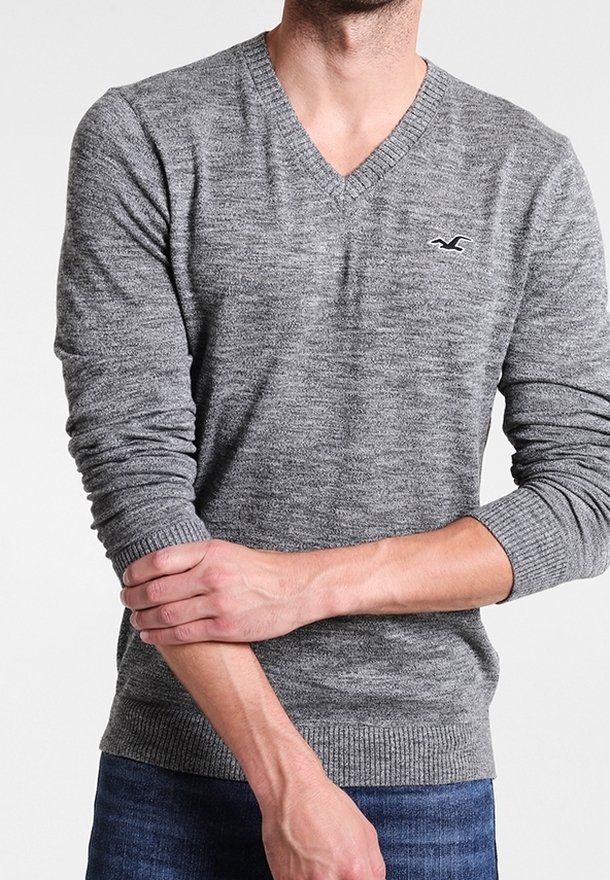 Šedý pletený svetr s výstřihem do V a žebrovanými manžetami. Obsahuje malé logo na hrudi a texturovaný vzor látky.