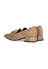 Mocasines de piel marrón claro con tacón bajo y puntera afilada, que presentan una hebilla decorativa y una textura lisa. La suela negra añade contraste.