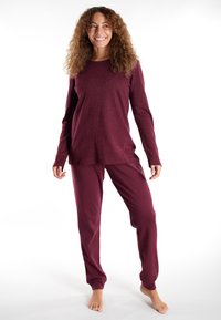 Maroon pajama set featuring a long-sleeve top with subtle leopard print and matching pants. Soft fabric with a relaxed fit.