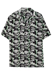 Chemise à manches courtes avec un motif graphique en noir et blanc d'yeux et de lèvres avec des accents verts, fabriquée en tissu léger.