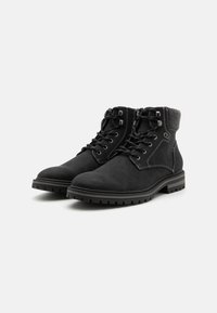 Botas de ante negras con un cuello de tela gris texturizada, diseño de cordones, puntera reforzada y suela de goma duradera con tracción.