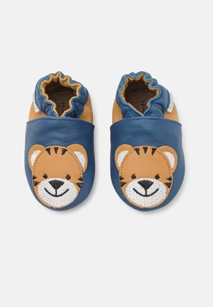 Chaussons en cuir pour bébé avec un corps bleu et un design de visage de tigre beige. Ils sont dotés d'une ouverture élastiquée froncée pour un enfilage facile. Semelle douce.