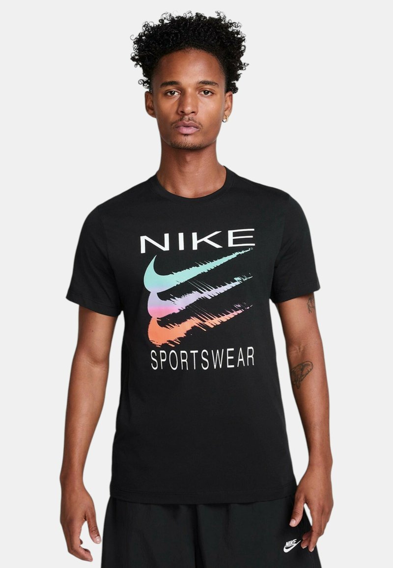 Camiseta de algodón negra con un gran logotipo de "NIKE" y tres diseños de swoosh en colores pastel. Cuello redondo y mangas cortas.