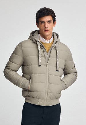 Giacca puffer grigia chiara con cappuccio, chiusura con zip e tasche laterali. Presenta polsini elastici e branding "POLO CLUB" sui lacci.