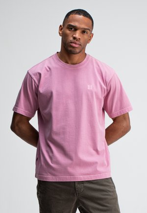 Rosa Baumwoll-T-Shirt mit kurzen Ärmeln und Rundhalsausschnitt; hat ein kleines Logo auf der Brust und eine lockere Passform.