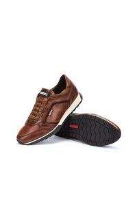Zapatillas de cuero marrón con parte superior texturizada, cordones elásticos, mediasuela blanca y suela de goma negra con un patrón de banda de rodadura en zigzag.