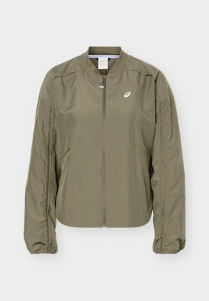 Veste bomber vert olive clair avec fermeture éclair complète, poignets élastiques, deux poches latérales et un petit logo blanc Asics sur la poitrine.