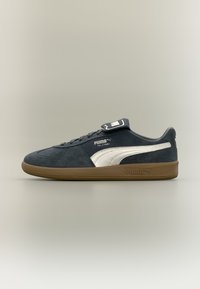Blue suede sneaker with white Puma stripe, brown rubber sole, and padded tongue. Features rounded toe and stitched accents.