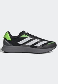 Scarpa da corsa nera con tomaia in rete, dettagli a strisce bianche, tallone verde e particolari, con una suola intermedia grigia testurizzata contrassegnata "LIGHTSTRIKE."