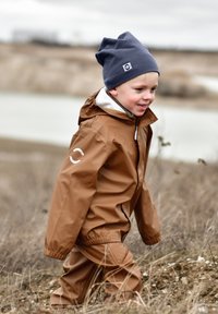 Waterdichte bruine jas met capuchon en bijpassende broek; grijze muts; beide hebben een gladde textuur en een eenvoudig ontwerp.