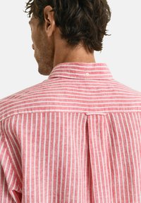 Gestreept button-up shirt in roze en wit, met een zachte textuur, een kraag en een plooidetail aan de achterkant voor een gemakkelijke beweging.