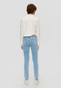 Lichtblauwe skinny jeans met een zachte textuur. Kenmerken zijn een hoge taille, vijf zakken en subtiele stiksels. Gecombineerd met een wit shirt.