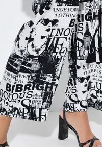 Geknipte broeken met een zwart-wit grafisch ontwerp met tekst en afbeeldingen, waaronder stadsgezichten en gezichten. Textuurstof met een relaxte pasvorm.