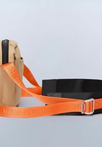 Borsa in nylon beige con zip nera, dotata di una tracolla arancione regolabile con etichetta "Napapijri." Include una cintura nera con una fibbia in metallo argentato.