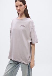Loose-fit, light purple t-shirt made of cotton, features round neckline, short sleeves, and embroidered "PIROUETTES" in dark red on the front.
