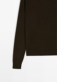Maglione marrone scuro con una texture morbida, maniche lunghe e orlo dritto. Il materiale appare leggero e adatto per essere indossato a strati.